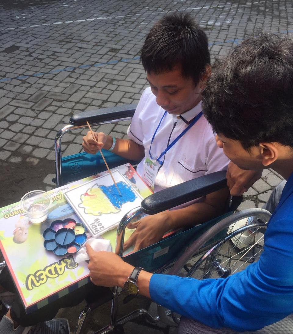 Salah satu anak disabilitas terlihat sedang melukis dengan cat air didampingi mahasiswa Teknik Industri Manufaktur Prodi Sarjana Terapan D-4 ITN Malang. (Foto: Istimewa)