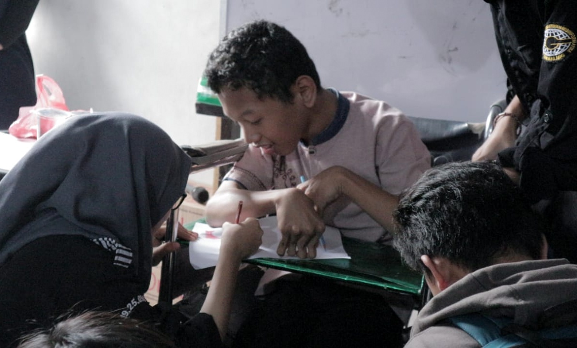 Tekun, mahasiswi ITN Malang mengajari anak disabilitas mewarna peta Indonesia. (Foto: Istimewa)
